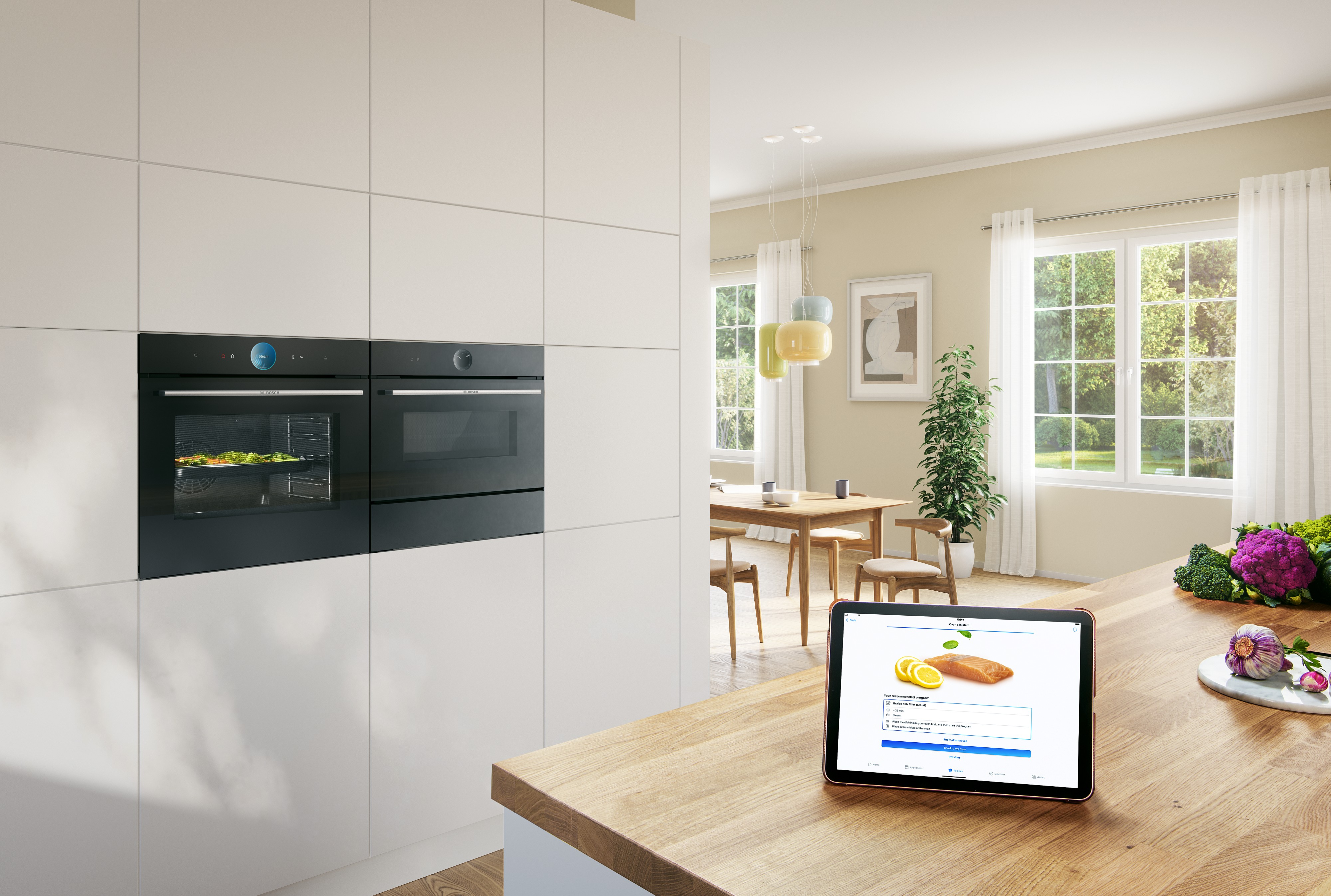 Bosch Einbauöfen schwarz in weißem Küchenhochschrank davor auf Küchentheke Tablet PC mit gestarteter Kochanwendung